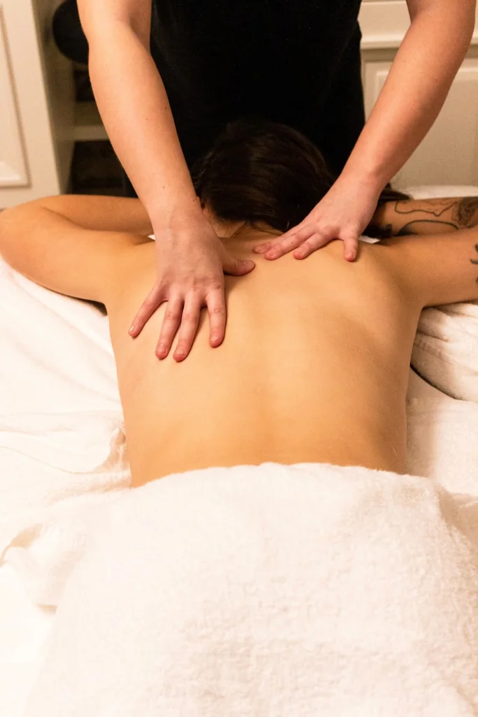Emma working across a client's upper back and shoulders during a sports massage treatment.